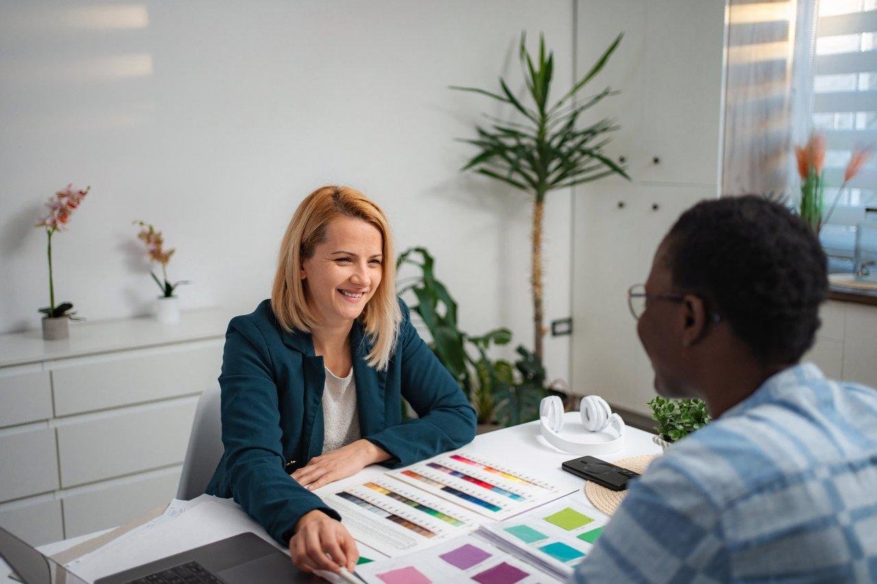 Consultation d'un architecte d’intérieur avec un client, sélection de matériaux et palettes de couleurs pour un projet design.